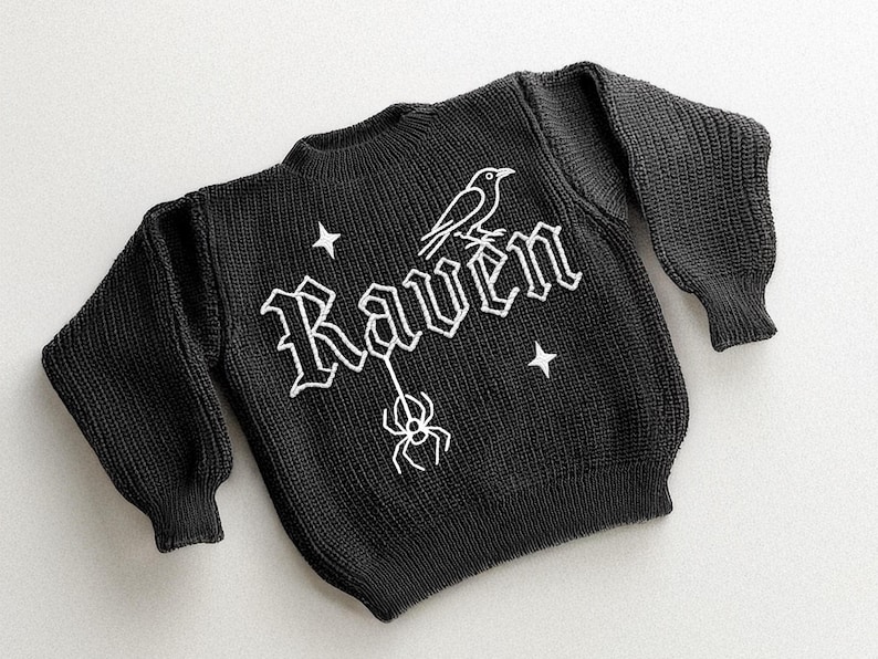 May include: Black knit sweater with the word "Raven" in white gothic lettering, a white raven, a spider, and two white stars. The sweater has long sleeves and a crew neck.