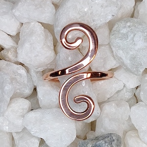 May include: A rose gold ear cuff with a double spiral design. The cuff is made of metal and is designed to be worn on the upper part of the ear.