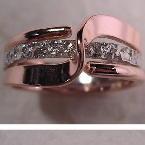 May include: Two intertwined rings, one rose gold and one silver, with a row of small diamonds set in the silver band. The rings are both textured.