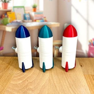May include: Three small rocket-shaped drawer pulls in blue, teal, and red. The rocket bodies are white with a screw in the back.