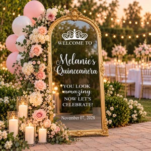 May include: An arched gold-framed mirror sign featuring white text that reads: WELCOME TO Melanie's Quinceañera YOU LOOK amazing. NOW LET'S CELEBRATE! November 07, 2028. The mirror is decorated with pink balloons and pink and white floral arrangements.