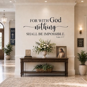 May include: A black wall decal featuring the text FOR WITH GOD nothing SHALL BE IMPOSSIBLE. Luke 1:37 in a mix of serif and script fonts. The decal is applied to a light-colored wall above a wooden console table with a floral arrangement.