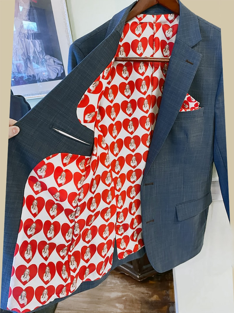 May include: A blue blazer with a red and white patterned lining featuring a repeated image of a woman. The lining is visible when the blazer is open.