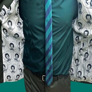 May include: A dark green blazer with a white lining featuring a repeating pattern of a woman's face in a heart shape.