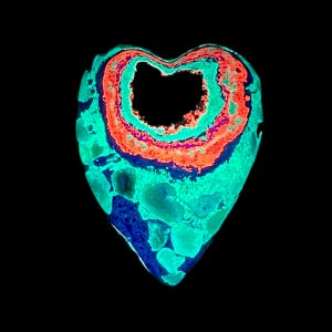 May include: A heart-shaped stone with a glowing, layered appearance. The layers feature vibrant colors: teal, orange, purple, and blue. The center of the heart is a dark void, creating a striking contrast against the colorful exterior. The stone is set against a black background.
