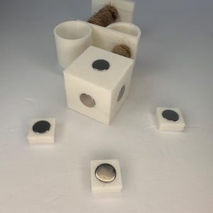 May include: Five white square blocks with round silver magnets on top. The blocks are arranged in a semi-circle pattern.