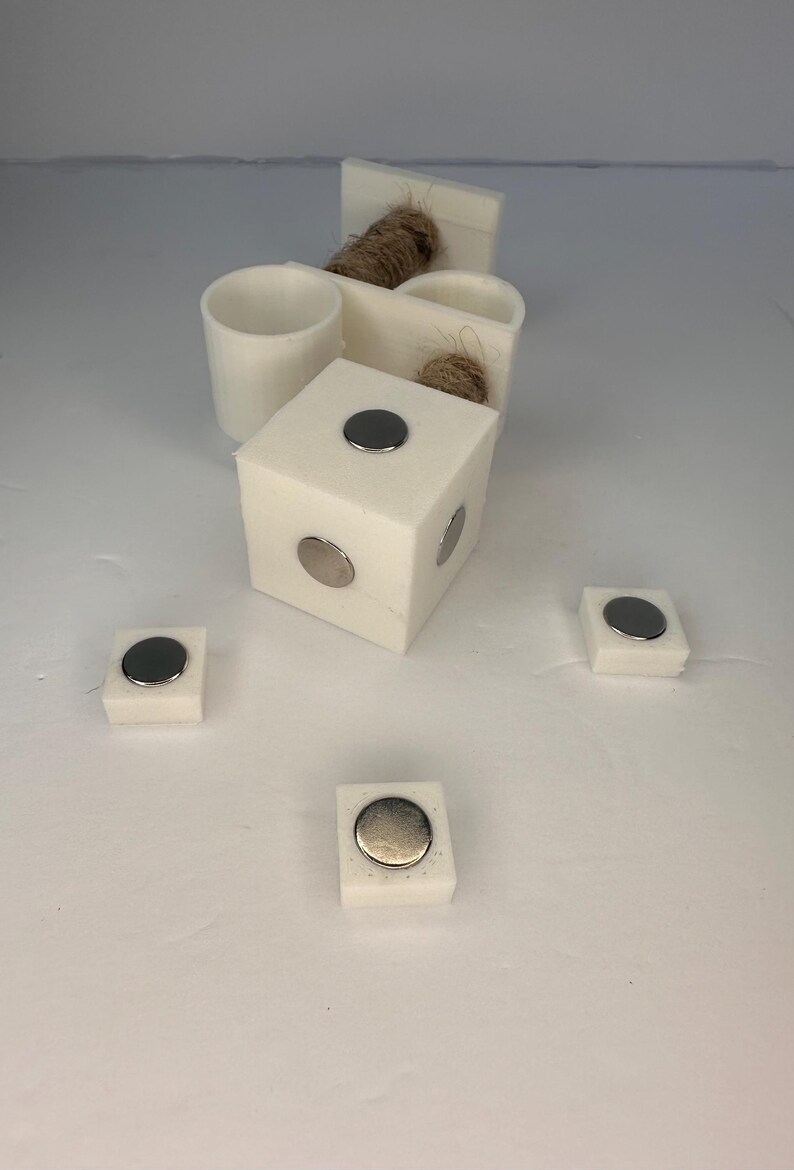 May include: Five white square blocks with round silver magnets on top. The blocks are arranged in a semi-circle pattern.