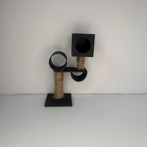 May include: A black cat tree with a square platform, a round platform, and a rope-covered post. The cat tree is made of wood and has a natural rope texture.