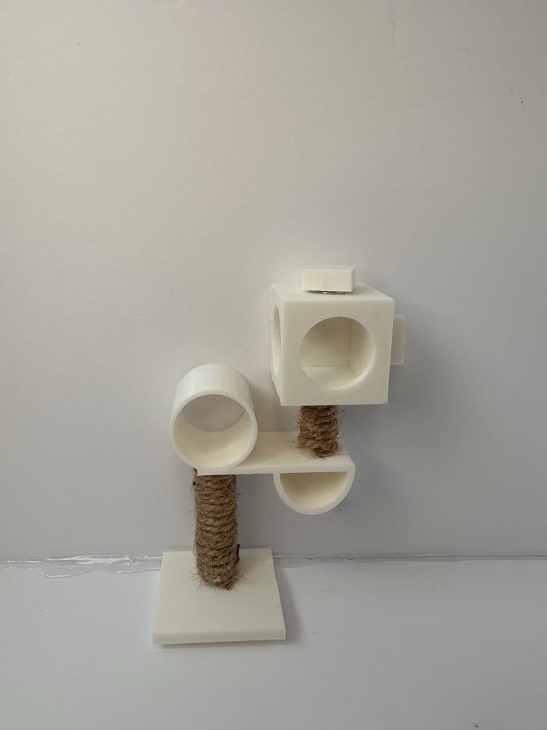 May include: White cat tree with a round platform, a square platform, and a rope scratching post. The cat tree has a small, round opening on the top platform.