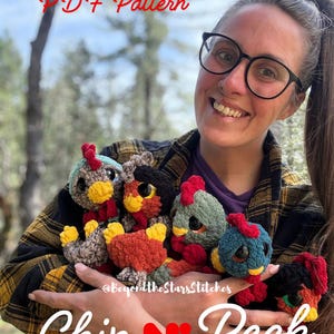 May include: A collection of colorful, crocheted chicken toys with red, yellow, and blue accents. The text "PDF Pattern" and "Chip N' Peck" are visible. The toys are held in a person's hands.