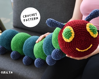May include: Crochet pattern for a colorful caterpillar toy. The caterpillar is made of green, blue, and red yarn and has a smiling face with yellow eyes. The pattern is available for purchase.