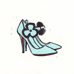 May include: A pair of light blue high-heeled shoes with a black flower accent on the strap.