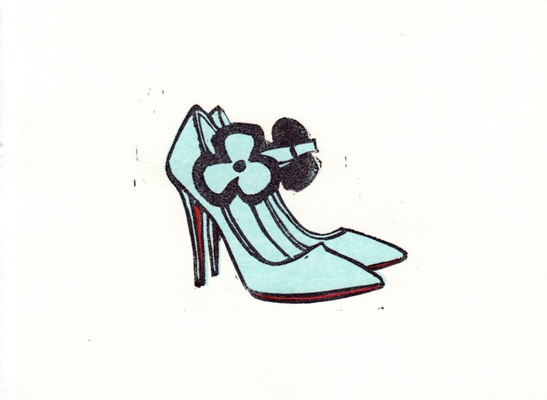 May include: A pair of light blue high-heeled shoes with a black flower accent on the strap.