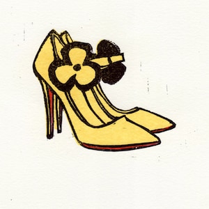 May include: A pair of yellow high-heeled shoes with a black flower accent on the front.