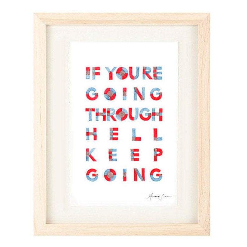 May include: Framed print with a white background and the text "If you're going through hell keep going" in red and blue letters. The letters are made up of small squares. The print is signed "Anna Sui" in the bottom right corner.