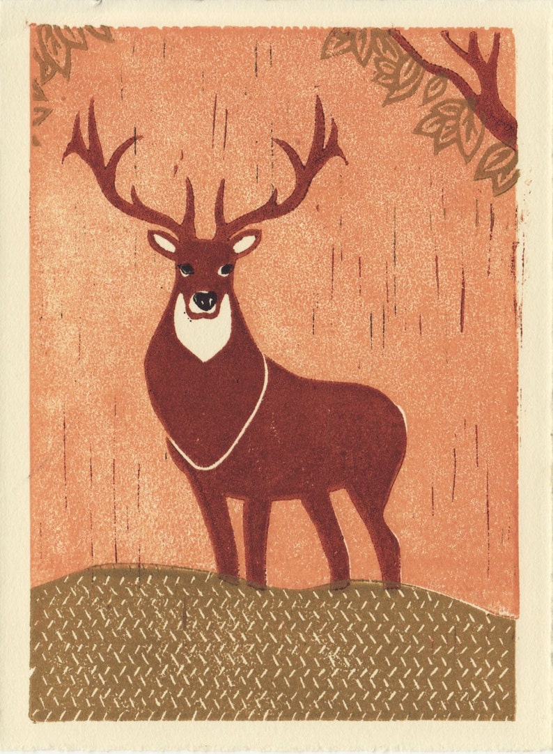 May include: A brown deer with large antlers stands on a brown and green patterned ground. The deer is facing forward with its head held high. The background is a light orange color with a brown tree branch with leaves in the upper right corner.