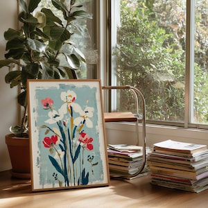 May include: A rectangular framed art print featuring a stylized floral illustration with white, red, and dark blue flowers set against a light blue background. The artwork is enclosed in a simple, light-toned wooden frame with a clean, flat edge.