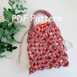 May include: A pink crocheted mesh bag with a red and white gingham lining. The bag has a drawstring closure and a loop handle. The bag is on a white surface with a green plant in the background. PDF Pattern.