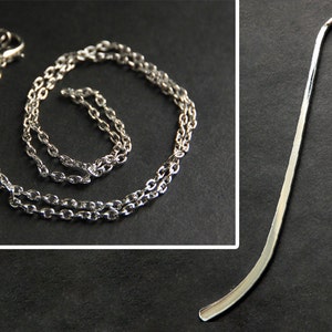May include: A silver chain necklace and a silver bookmark with a hook at the top.