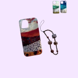 Puede incluir: Una funda de teléfono rectangular con un patrón abstracto multicolor de puntos rojos, blancos y negros, acompañada de un colgante de cuentas con abalorios marrones, beige y grises. Dos fundas adicionales con diseños oceánicos en azul y verde.