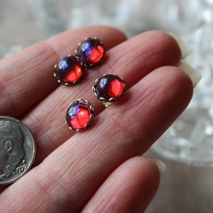 May include: Four red and blue iridescent glass cabochon earrings with silver settings.