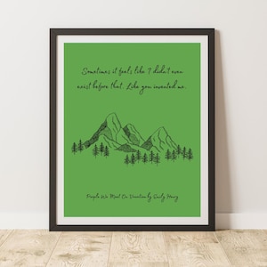 Op de afbeelding: Een ingelijste kunstdruk met een groene achtergrond. De print toont een zwarte lijntekening van bergen en bomen, met de quote "Sometimes it feels like I didn't even exist before that. Like you invented me." en de boektitel.
