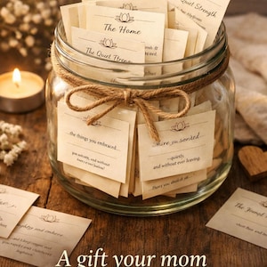 May include: A glass jar filled with small, cream-colored cards tied with twine. The cards have handwritten text and are labeled with phrases like "The Silent Nights" and "The Home." The jar is on a wooden surface with a lit candle and text that reads "A gift your mom will never forget."