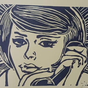 Puede incluir: Una impresión de linóleo azul y blanco de una mujer con el pelo corto, mirando hacia abajo y con la mano en la mejilla.