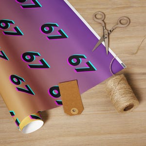 May include: A roll of gift wrap with a gradient purple and gold background, featuring the number "67" in black with a pink and teal outline. A pair of scissors, a brown tag, and twine are also present.