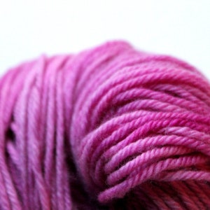 Op de afbeelding: Een close-up van een bol roze garen met een kleurverloop van lichtroze tot donkerroze.