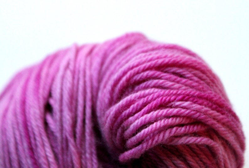 Op de afbeelding: Een close-up van een bol roze garen met een kleurverloop van lichtroze tot donkerroze.