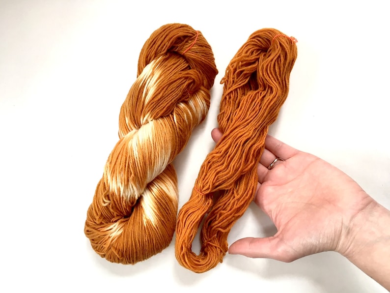 May include: Two skeins of yarn, one is a solid orange color and the other is a variegated orange and white color.