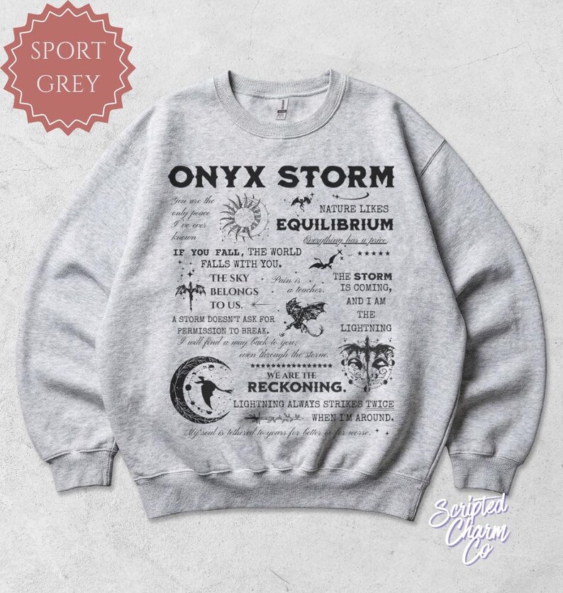May include: Sport grey sweatshirt with the text "ONYX STORM" and various graphics. The design includes phrases like "Nature likes equilibrium" and "We are the reckoning." The sweatshirt has a crew neck and long sleeves.