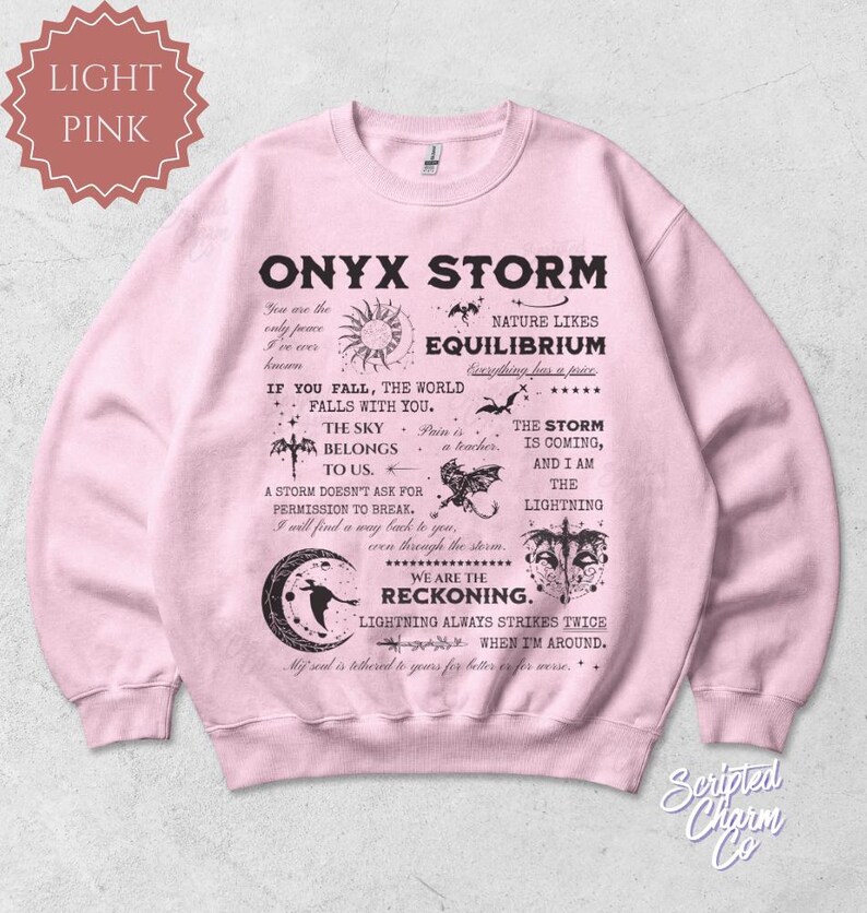 May include: Light pink sweatshirt with the text "ONYX STORM" and various graphics. The design includes phrases like "The sky belongs to us" and "We are the reckoning."