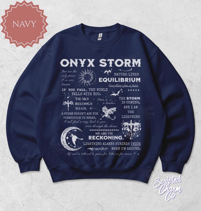 May include: Navy blue sweatshirt with the text "ONYX STORM" and various celestial and nature-themed graphics. The design includes phrases like "The sky belongs to us" and "We are the reckoning."