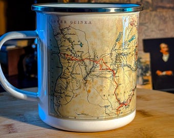 May include: White enamel mug with a vintage map design. The mug features a silver rim and handle, and the map shows the African continent with the text "LOWER GUINEA" and "MAKOLOLO".