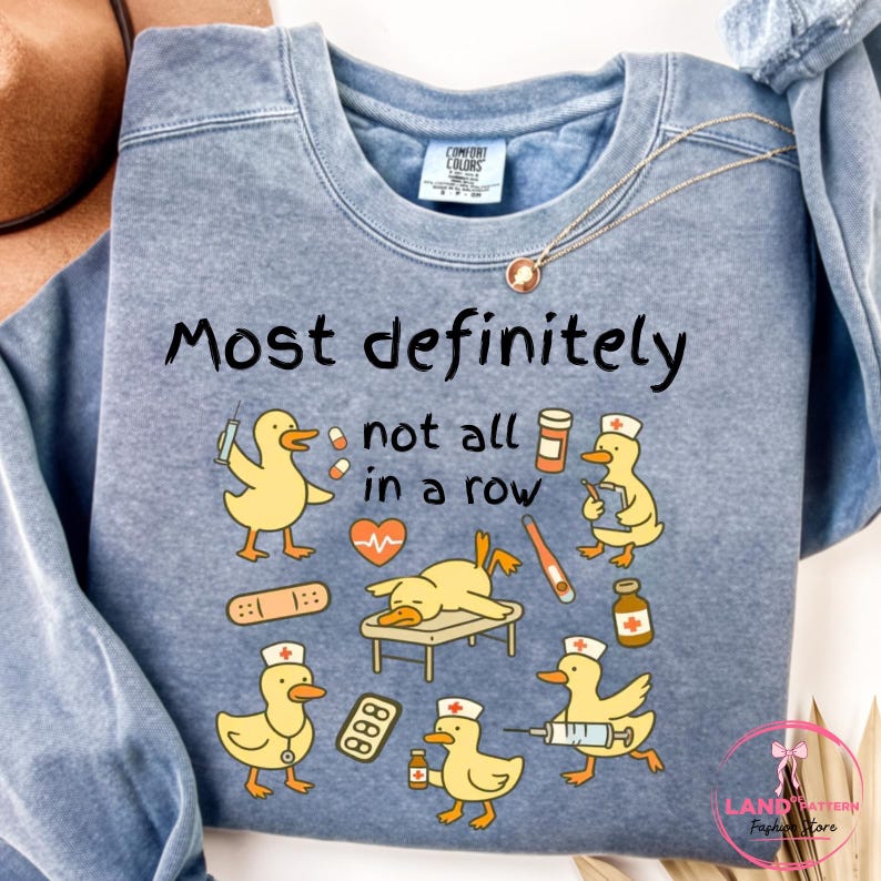 Pu&ograve; includere: Una felpa blu con la scritta "Most definitely not all in a row". Il design presenta anatre dei cartoni animati in ruoli medici, tra cui infermieri e pazienti. Le anatre sono gialle con cappelli bianchi e forniture mediche.