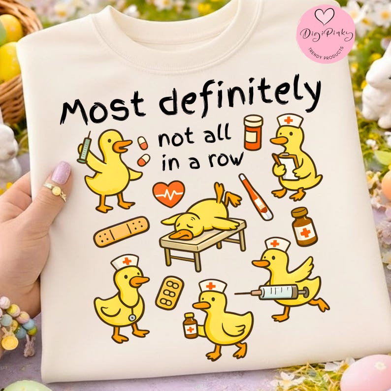 Pu&ograve; includere: Felpa color crema con una grafica giocosa con anatre gialle dei cartoni animati in ruoli medici, circondate da forniture mediche. Il testo "Most definitely not all in a row" &egrave; visualizzato sopra le anatre. Un logo Digi Pinky Trendy Products.