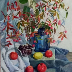 Classic still life with bright autumn foliage in a blue vase on the table red apples black grapes and lemon enhance the expressiveness color