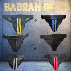 May include: Collection of athletic supporter-style protective gear in various colors. The gear features a pouch design with a waistband and straps. Some have colored stripes and zippers in yellow, blue, red, and silver. The brand name "BABRAH GEAR" is visible.