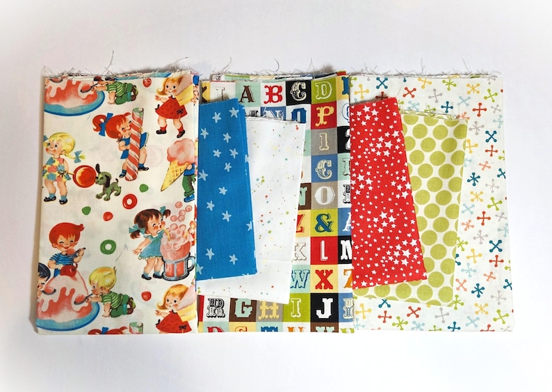 May include: A selection of fabric swatches featuring diverse patterns. Designs include children with ice cream, blue stars, white polka dots, red stars, and colourful letters. The fabrics are arranged side by side.