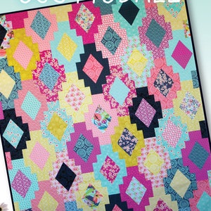 Puede incluir: Un edredón colorido con un patrón geométrico. El edredón presenta formas de diamante en varios colores, incluyendo rosa, azul, amarillo y negro. La palabra "SCOTTSDALE" está escrita en blanco en la parte superior. Hecho por Crazy Old Ladies.