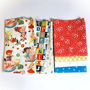 May include: A selection of patterned fabric pieces in various colours. One fabric has a red background with white stars. Other fabrics feature children, letters, and geometric designs. These fabrics are suitable for sewing and craft projects.