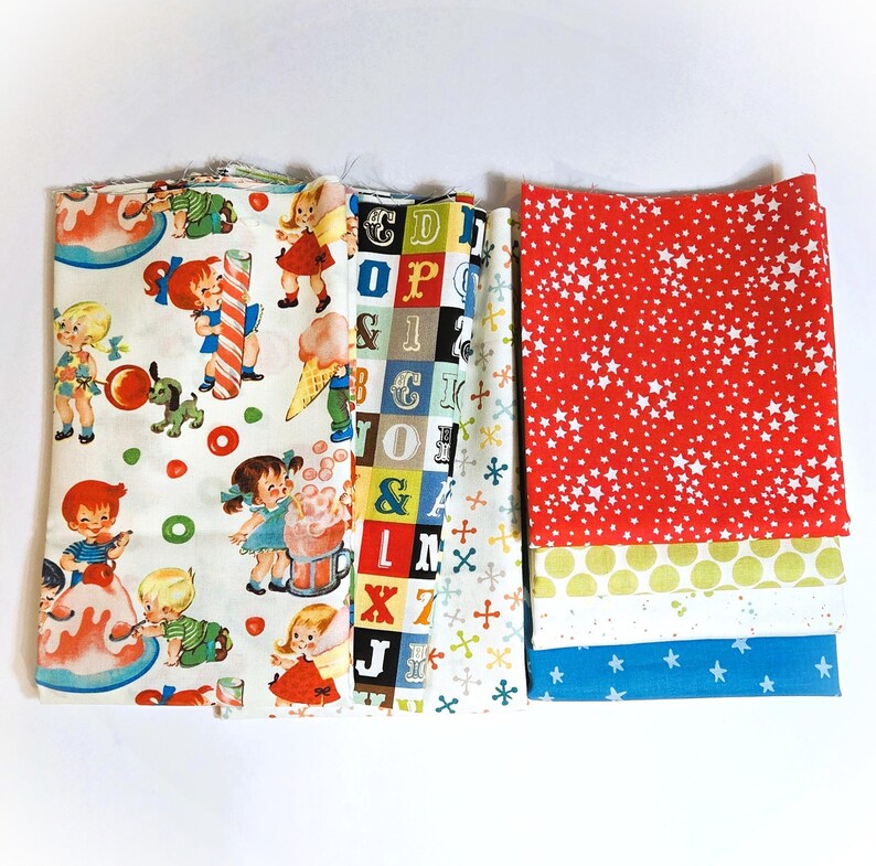 May include: A selection of patterned fabric pieces in various colours. One fabric has a red background with white stars. Other fabrics feature children, letters, and geometric designs. These fabrics are suitable for sewing and craft projects.