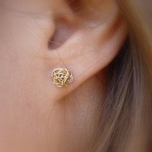 May include: Gold wire earrings in the shape of a ball. The earrings are small and delicate.