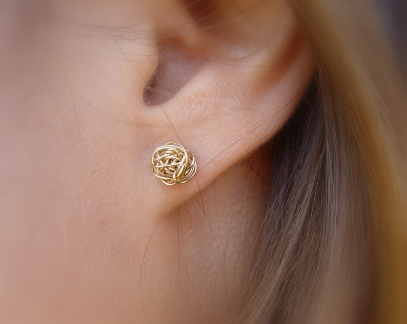 May include: Gold wire earrings in the shape of a ball. The earrings are small and delicate.