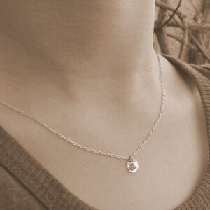 May include: A silver chain necklace with a hammered silver pendant.