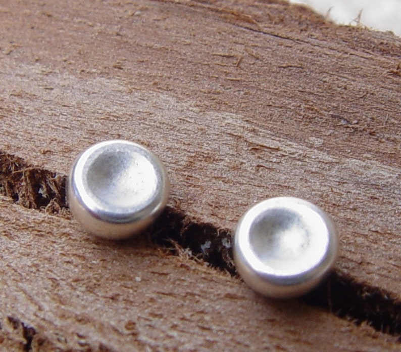 Op de afbeelding: Twee ronde, concave zilveren oorbellen met een gladde, gepolijste afwerking.