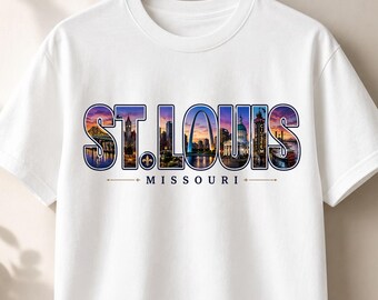 May include: A white short-sleeved t-shirt featuring a graphic print of the St. Louis skyline inside the bold text ST. LOUIS. The design includes the Gateway Arch, a fleur-de-lis, and the word MISSOURI centered below in a dark blue font.