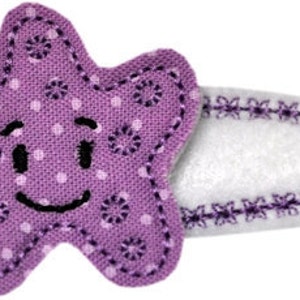 May include: Purple fabric starfish with a smiling face and white polka dots. The starfish is attached to a white fabric rectangle with a purple stitched border.